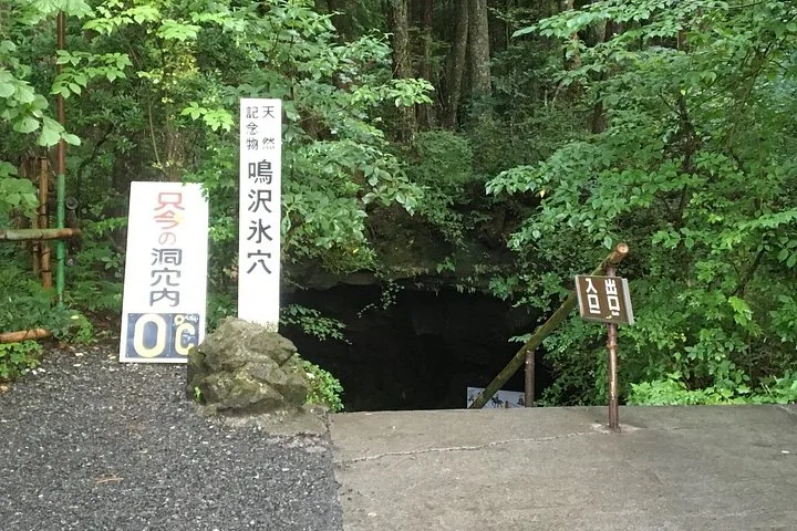Entrance to Narusawa Ice Cave with Japanese signs in the forest.